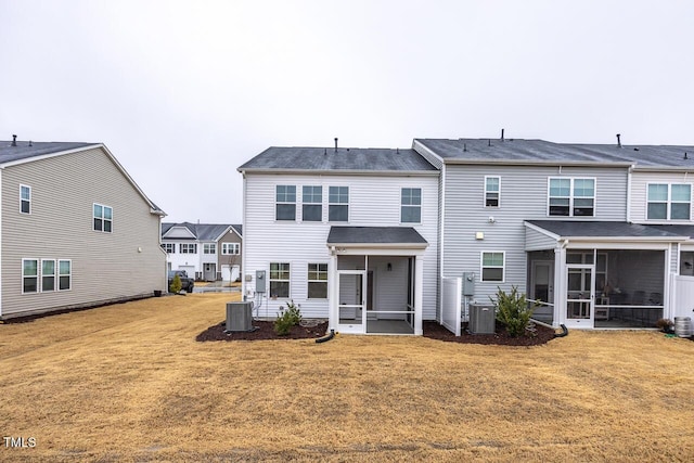 rear view of house featuring central air condition unit, a sunroom, and a yard