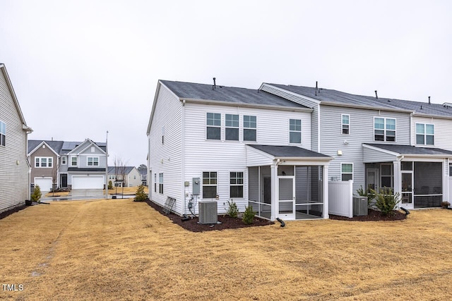 back of property featuring a sunroom, central AC unit, and a yard