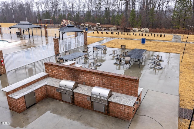 view of patio / terrace featuring a gazebo, an outdoor kitchen, and a grill