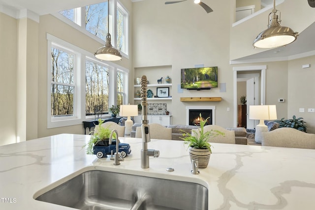 kitchen featuring light stone countertops, ceiling fan, and sink