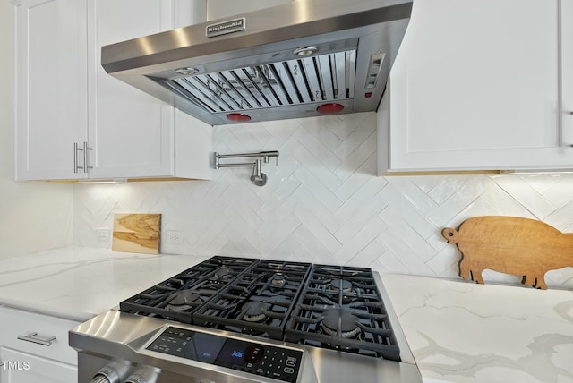 kitchen with ventilation hood, decorative backsplash, white cabinets, and light stone countertops