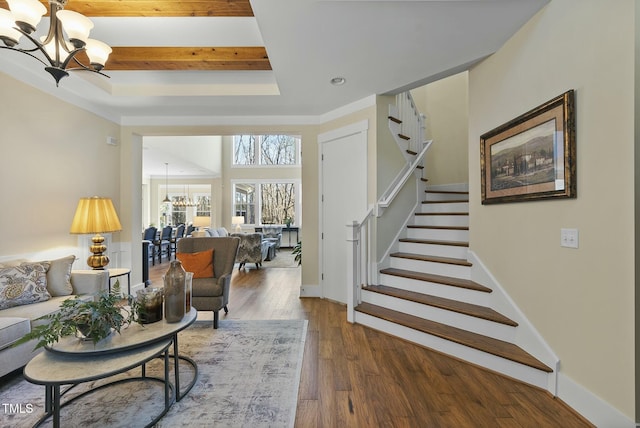 living room with dark hardwood / wood-style floors, a raised ceiling, and an inviting chandelier