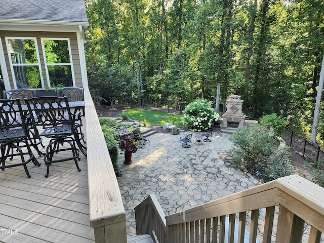 wooden terrace with a patio area and an outdoor stone fireplace