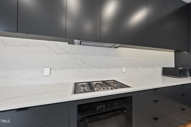 kitchen with tasteful backsplash, stainless steel gas cooktop, and oven