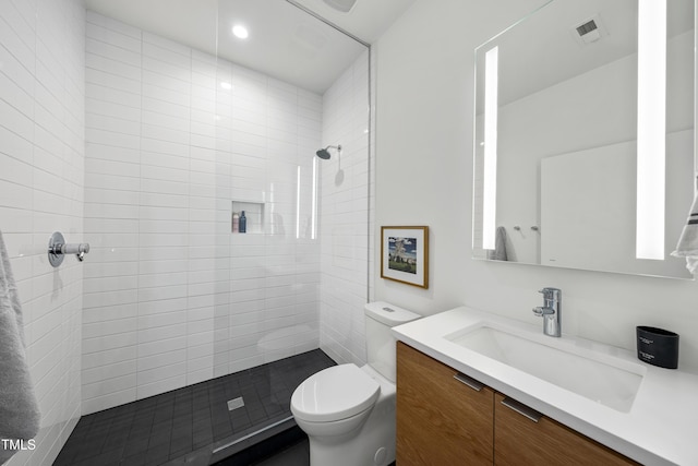 bathroom featuring vanity, toilet, and tiled shower