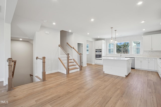 kitchen featuring white cabinets, hanging light fixtures, a center island, and decorative backsplash