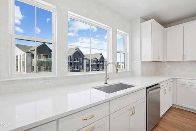 kitchen with sink, a healthy amount of sunlight, white cabinetry, and stainless steel dishwasher