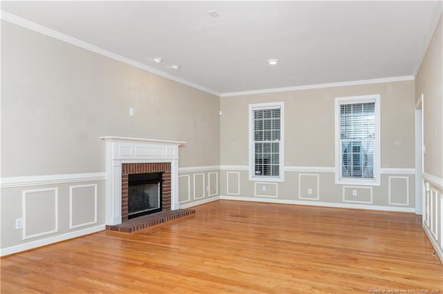 unfurnished living room with light hardwood / wood-style flooring, a brick fireplace, and ornamental molding