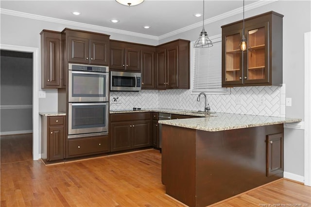 kitchen featuring light stone counters, pendant lighting, stainless steel appliances, and sink