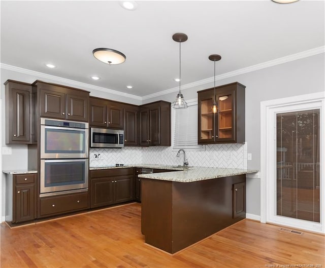 kitchen featuring kitchen peninsula, appliances with stainless steel finishes, dark brown cabinetry, and pendant lighting