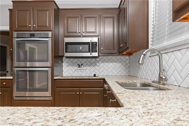 kitchen with stainless steel appliances, light stone counters, tasteful backsplash, and sink