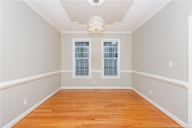 spare room featuring a notable chandelier, crown molding, and light hardwood / wood-style flooring