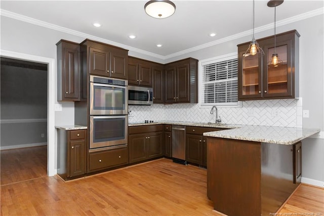 kitchen with decorative light fixtures, light wood-type flooring, ornamental molding, and appliances with stainless steel finishes