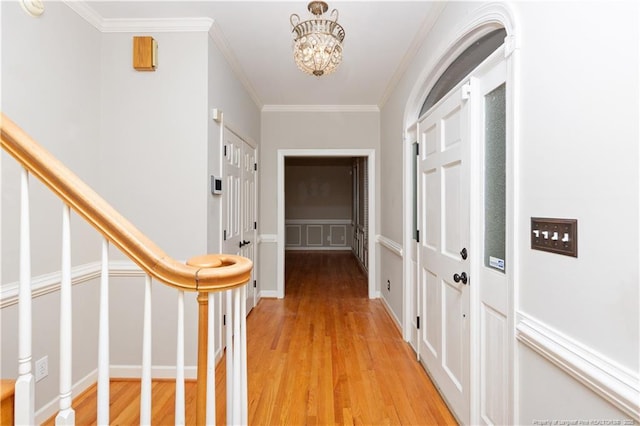 hall featuring ornamental molding, a chandelier, and light wood-type flooring