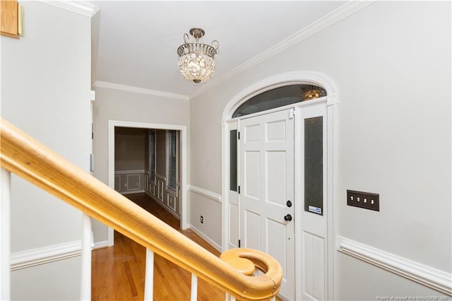 entrance foyer with hardwood / wood-style floors, crown molding, and an inviting chandelier