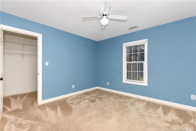 unfurnished bedroom featuring ceiling fan, carpet floors, a textured ceiling, and a closet