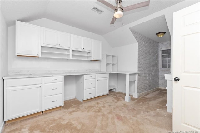 unfurnished office with light colored carpet, ceiling fan, lofted ceiling, and brick wall