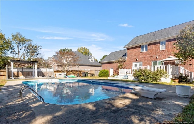 view of pool with a diving board, a patio, and a deck