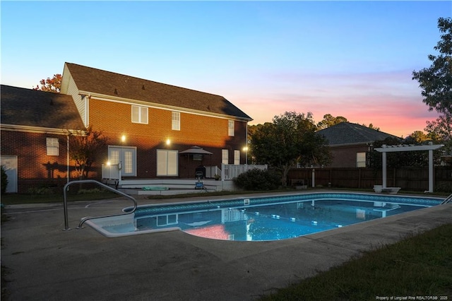 pool at dusk with a patio area