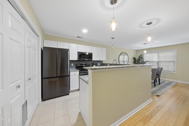 kitchen featuring white cabinetry, hanging light fixtures, stainless steel appliances, and light stone counters