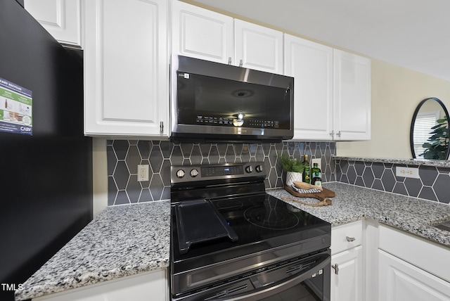 kitchen featuring tasteful backsplash, white cabinetry, light stone countertops, and black appliances