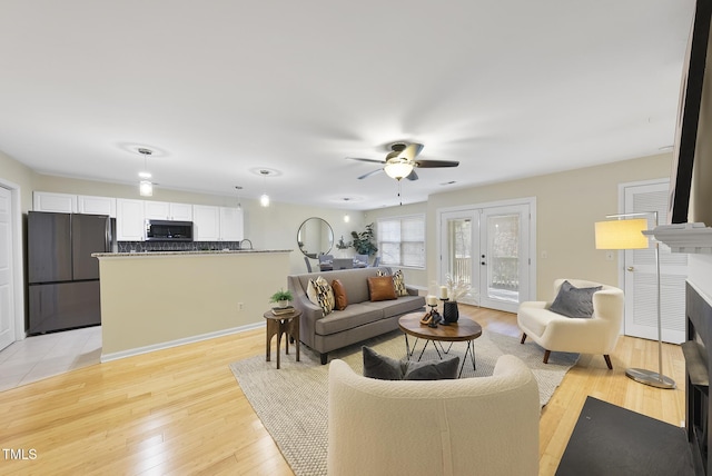 living room with a tiled fireplace, ceiling fan, and light hardwood / wood-style floors