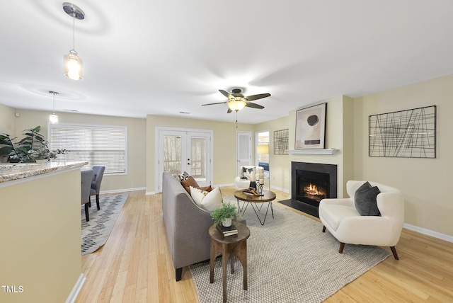 living room with ceiling fan, light hardwood / wood-style floors, and french doors