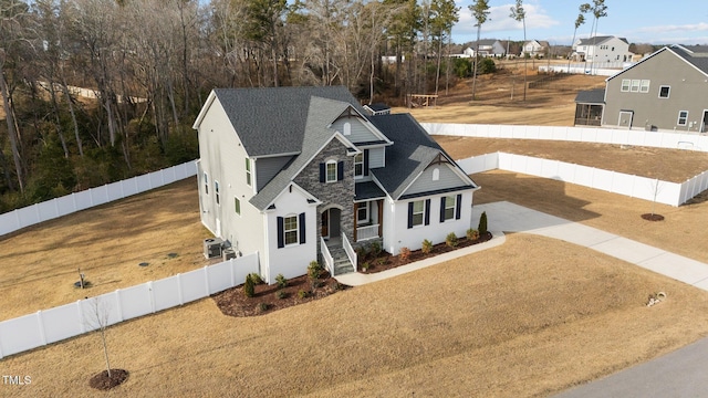 view of front of property with driveway, stone siding, and a fenced backyard