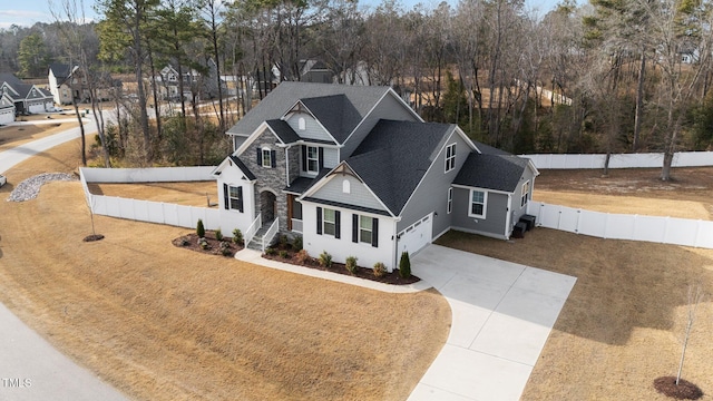 view of front facade featuring a garage, fence, concrete driveway, stone siding, and a front lawn