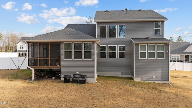 back of house featuring a sunroom, a fenced backyard, a lawn, and a gate