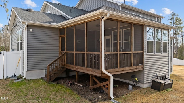 rear view of property with roof with shingles, fence, and a sunroom