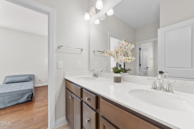 bathroom with double vanity, wood finished floors, a sink, and baseboards