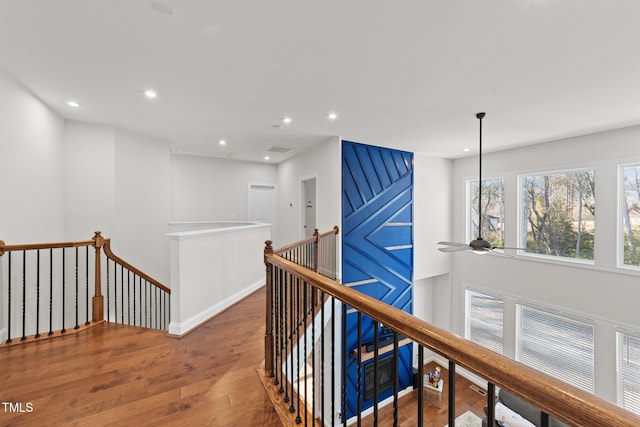 hall with recessed lighting, baseboards, wood finished floors, and an upstairs landing