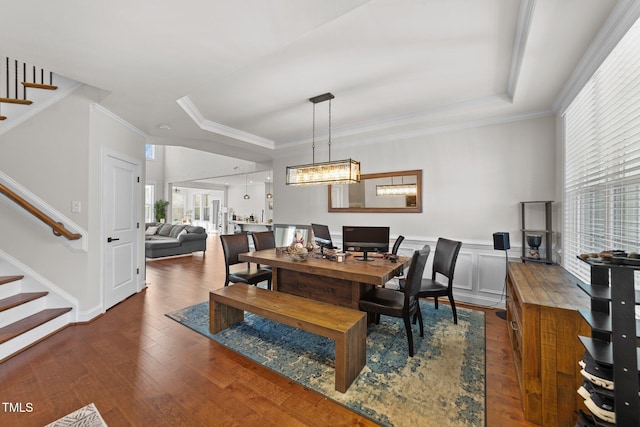 dining area featuring stairs, a tray ceiling, wood finished floors, and crown molding