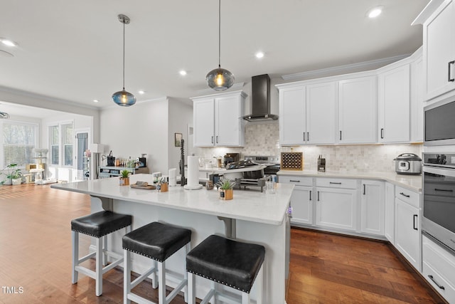 kitchen featuring appliances with stainless steel finishes, backsplash, white cabinets, and wall chimney range hood