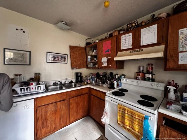 kitchen with a textured ceiling, white appliances, and sink