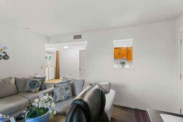 living room featuring hardwood / wood-style floors, a textured ceiling, and washer / clothes dryer