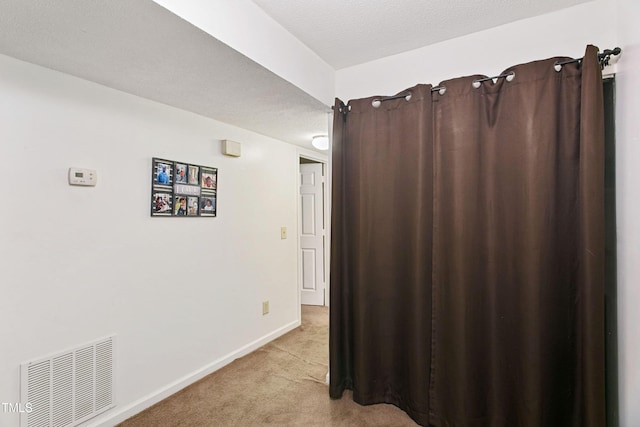 corridor with a textured ceiling and light colored carpet