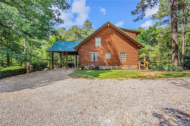 329 Silver Grove Church Rd, Rockingham, NC 28379 - view of side of home with log siding, driveway, a carport, central air condition unit, and metal roof