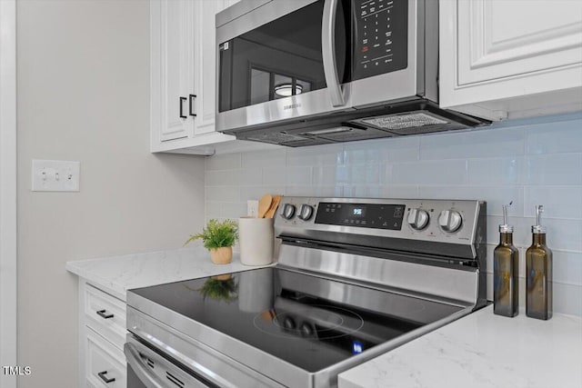 kitchen with stainless steel appliances, white cabinetry, backsplash, and light stone counters