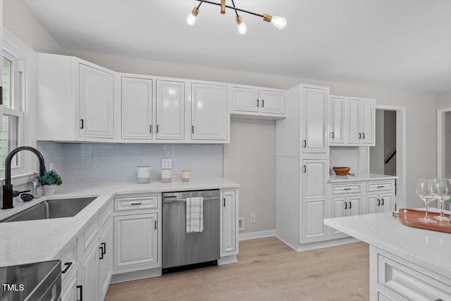 kitchen featuring sink, white cabinetry, tasteful backsplash, stainless steel dishwasher, and light hardwood / wood-style floors