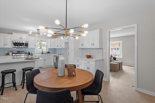 dining space with a notable chandelier, light hardwood / wood-style floors, and sink