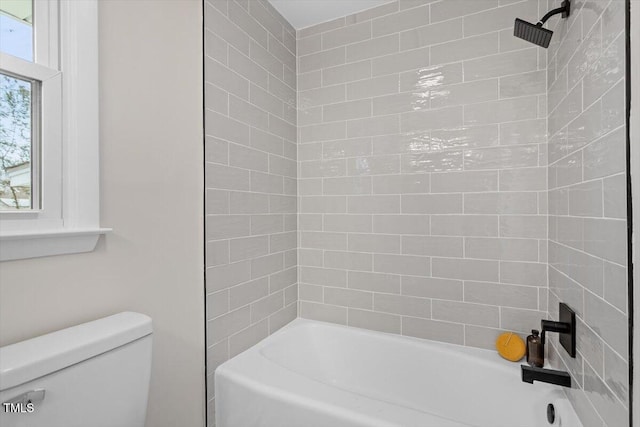 bathroom featuring toilet and tiled shower / bath