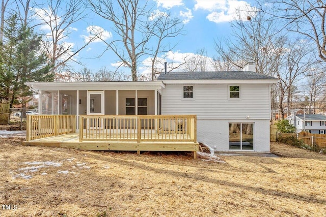 rear view of property with a yard, a sunroom, and a deck