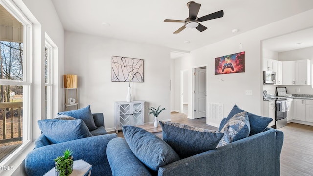 living room with ceiling fan, a wealth of natural light, and light hardwood / wood-style flooring