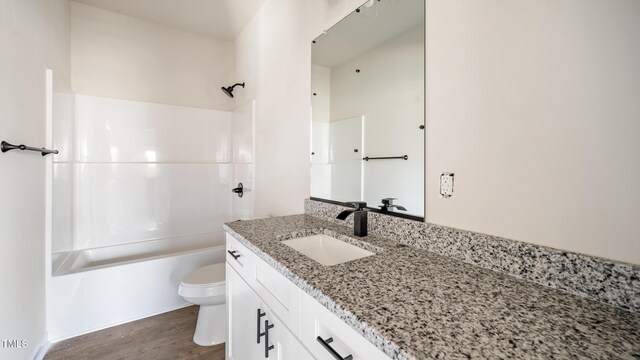 full bathroom featuring hardwood / wood-style floors, vanity, toilet, and tub / shower combination