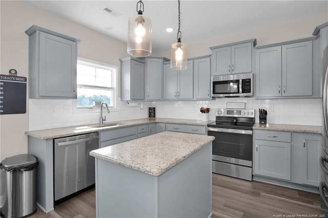 kitchen featuring gray cabinetry, a kitchen island, hanging light fixtures, and appliances with stainless steel finishes