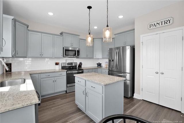 kitchen with sink, a center island, hanging light fixtures, decorative backsplash, and appliances with stainless steel finishes