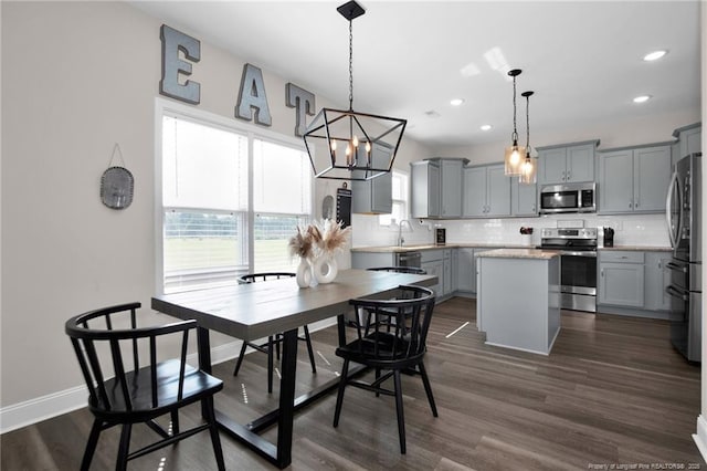 dining room with a notable chandelier, sink, and dark wood-type flooring