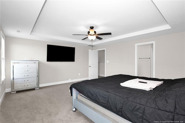 bedroom featuring light carpet, a raised ceiling, and ceiling fan